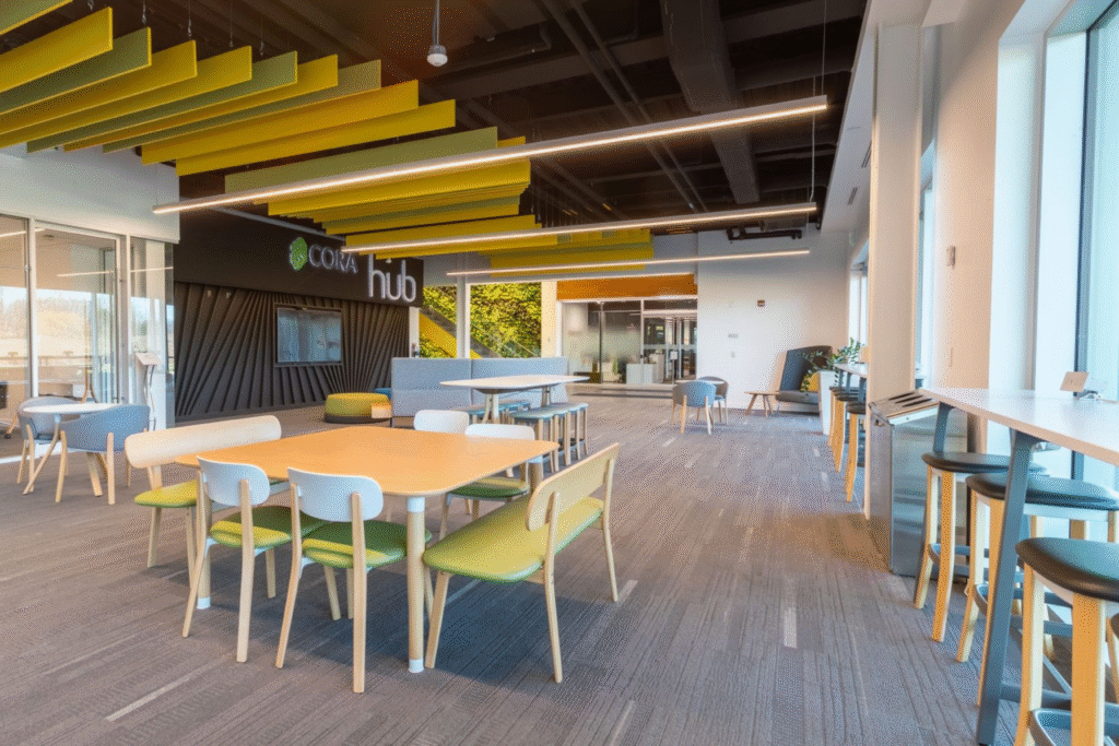 Collaborative hub area at Cora GRID coworking space in Waterloo featuring modern tables, colorful seating, bright natural light, and open design for networking and team meetings.