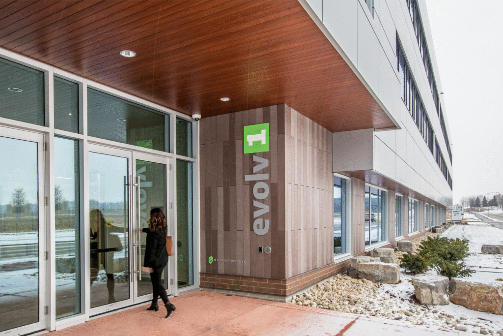 Main entrance of evolv1 building in Waterloo featuring modern glass doors, sustainable architectural design, wood-paneled ceiling, and prominent green evolv1 signage