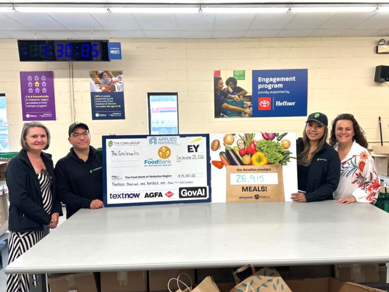 The Cora Group team poses with the Food Drive Fundraiser cheque and meals sign